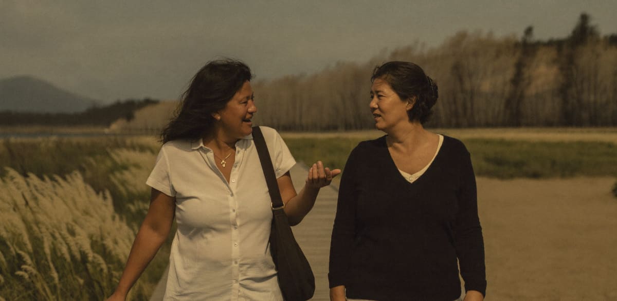 Two women walking and talking on a coastal boardwalk