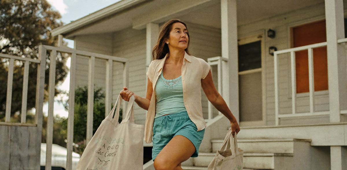 A woman carrying grocery bags up her front steps