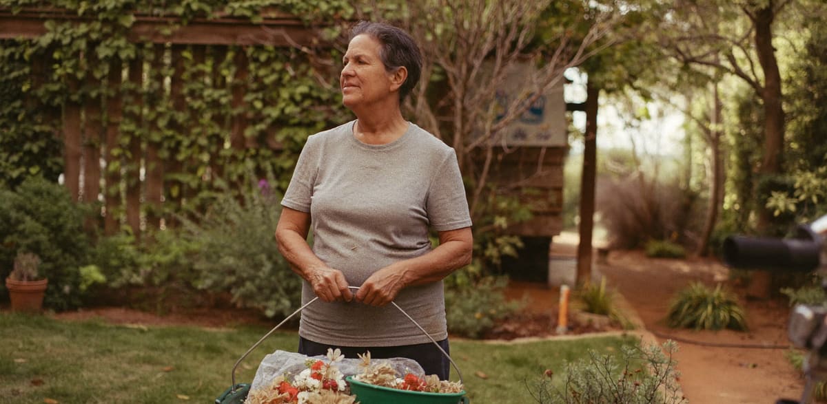 A woman standing in her garden holding a trug of cut flowers