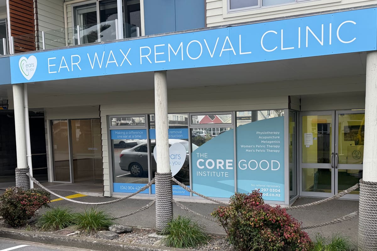 The clinic at 2 Seaview Road from the street. A long blue Ear Wax Removal Clinic sign runs above the veranda, and CoreGood's own signage covers the window below it, beside the glass entry doors.